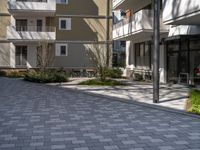 empty walkway between two beige building with parking spaces in front of them and trees on either side