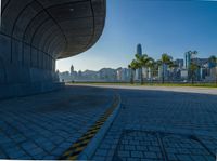 a large tunnel on the road with palm trees in the background and buildings in the distance