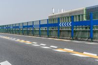 a man is standing next to a blue fence on the street near an urban building