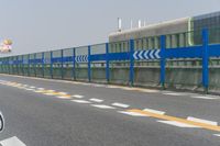 a man is standing next to a blue fence on the street near an urban building