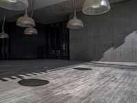 a building with several lamps in it and a wooden floor below them that is all lined with black curtains