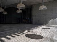 a building with several lamps in it and a wooden floor below them that is all lined with black curtains