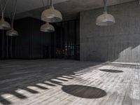 a building with several lamps in it and a wooden floor below them that is all lined with black curtains