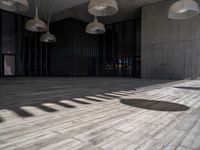 a building with several lamps in it and a wooden floor below them that is all lined with black curtains