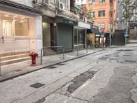 a red fire hydrant in the middle of a empty street in front of some buildings