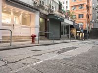 a red fire hydrant in the middle of a empty street in front of some buildings