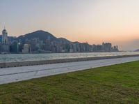 a view of the city from across the water from a man sitting by a bench