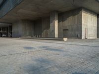 a concrete building with the top closed down in it's courtyard and a woman sitting in a chair on the sidewalk