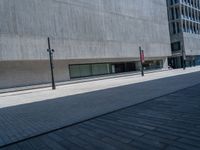 an empty sidewalk along a city street on a bright day with buildings behind it and a stop sign