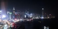 city lights on a hazy night by the water with a boat in the foreground