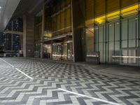 a sidewalk at night and an empty bus stop at the end of the street behind it