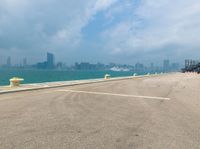 a large body of water next to a city skyline and a road with yellow poles on either side