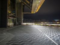 a black and white square on a brick floor with lights above it on an outdoor platform