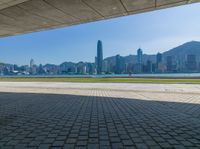 a man sitting down reading under a covered walkway near the beach and mountains in the distance