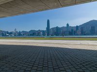 a man sitting down reading under a covered walkway near the beach and mountains in the distance