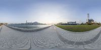 a fish - eye view photo of the grass and walkways with a large body of water in the background