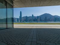 a view of a city from inside a building looking out over a bay to the city and mountains