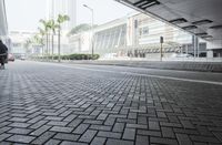 a person riding a red motorcycle on a brick road next to buildings and palm trees