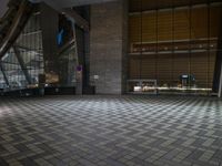 the floor is tiled in the shape of squares and has a lot of windows with lights on