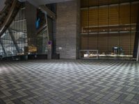 the floor is tiled in the shape of squares and has a lot of windows with lights on