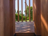 the large wood building has columns on each side, and two windows looking into a garden