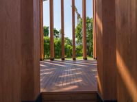 the large wood building has columns on each side, and two windows looking into a garden