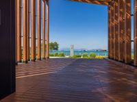 an open porch with several wooden benches and a view of the ocean through it is the sun