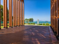 an open porch with several wooden benches and a view of the ocean through it is the sun