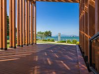 an open porch with several wooden benches and a view of the ocean through it is the sun