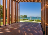 an open porch with several wooden benches and a view of the ocean through it is the sun