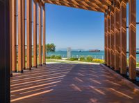 an open porch with several wooden benches and a view of the ocean through it is the sun