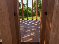 wooden planks on a wood walkway leading into a green yard and lake through the gate