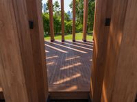 wooden planks on a wood walkway leading into a green yard and lake through the gate