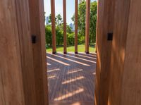 wooden planks on a wood walkway leading into a green yard and lake through the gate