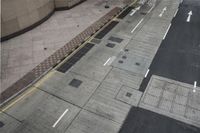 the sidewalk has multiple markings and a traffic light at it's end with a traffic cone in front of it