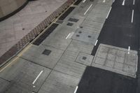 the sidewalk has multiple markings and a traffic light at it's end with a traffic cone in front of it