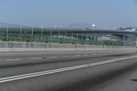 the motorcycle is going down the freeway by the bridge and into the distance are mountains