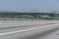 the motorcycle is going down the freeway by the bridge and into the distance are mountains