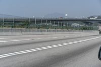 the motorcycle is going down the freeway by the bridge and into the distance are mountains