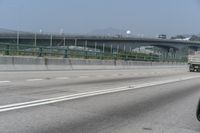 the motorcycle is going down the freeway by the bridge and into the distance are mountains