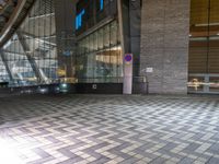 the building has a checkered tiled floor and a wall with large windows and lighting