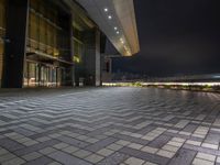 the sidewalk and walkway outside an office building at night near a dock with lights on