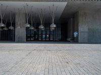 the stone floor of an empty building with lamps hanging from the ceiling and brick floors