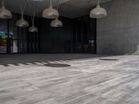 wooden flooring inside of a big building under multiple lamps hanging from a ceiling over it