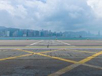 empty runway with cityscape in background and blue sky and clouds above them in hong kong kong