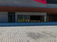 a brick walkway in front of an auditorium building with people standing at the doors in front