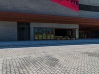 a brick walkway in front of an auditorium building with people standing at the doors in front