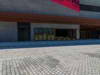 a brick walkway in front of an auditorium building with people standing at the doors in front