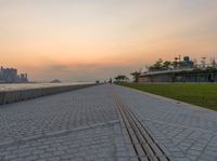 a beautiful, empty sidewalk near a beach during the sunrise as viewed from the water's edge