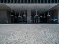 a building with various lamps in front of it on a brick floor and stone pillars